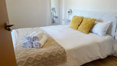 a white bed with towels and pillows on it at Dúplex con terraza by Prestigi in Terrassa