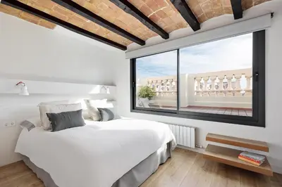 a bedroom with a white bed and a large window at Enjoy Apartments La Riera Penthouse in Barcelona
