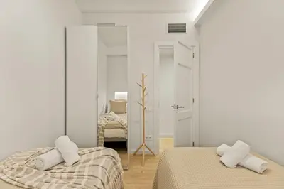 a white bedroom with two beds and a mirror at Modern & stylish apartment in Barcelona in Barcelona