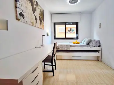 a bedroom with a desk and a bed with a window at Duplex con piscina en Rubí in Rubí