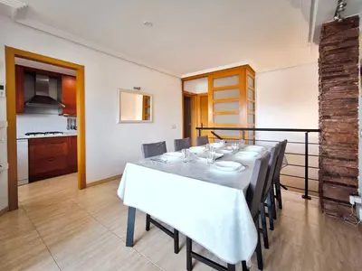 a dining room with a white table and chairs at Duplex con piscina en Rubí in Rubí