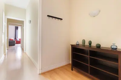 a living room with white walls and a wooden dresser at Elegance and Comfort in Barcelona, 4Bedroom Apartment in the Most Exclusive Area in Barcelona