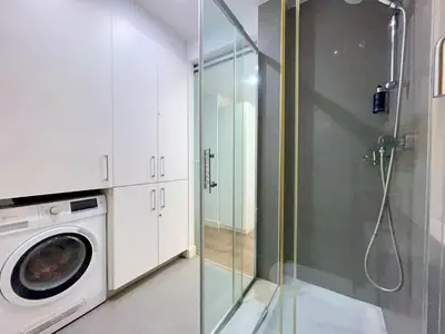 a bathroom with a washing machine and a glass shower at BarcelonaForRent Tucson Suites in Barcelona