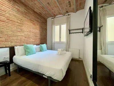 a bedroom with a large white bed with a brick wall at BarcelonaForRent Tucson Suites in Barcelona