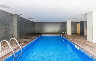 a large swimming pool with blue water in a room at Magnífica Isla de la playa Fórum y CCIB in Sant Adria de Besos