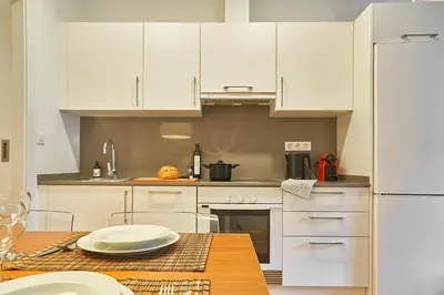 a kitchen with white cabinets and a wooden table at Catalan Comfort near Sagrada Familia by MyRentalHost in Barcelona