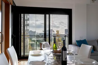 a dining room table with white chairs and a view of the city at Apartment close to Diagonal Beach in Barcelona