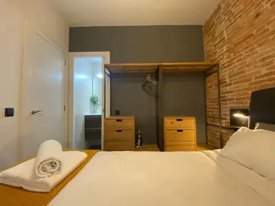 a bedroom with a white bed and a brick wall at Cosy Urban Oasis 1BD in Poble Sec By MyRentalHost in Barcelona