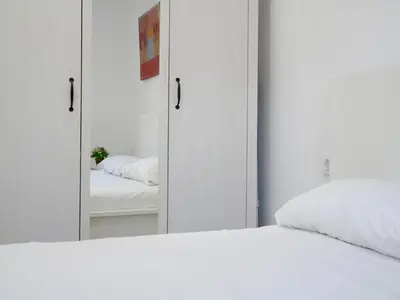 a bedroom with a white bed and a mirror at MarBarcelona Apartments Mas in Hospitalet de Llobregat