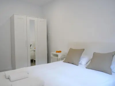 a white bedroom with a large white bed and a mirror at MarBarcelona Apartments Mas in Hospitalet de Llobregat