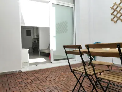 a chair and a table in a room with a window at MarBarcelona Apartments Mas in Hospitalet de Llobregat