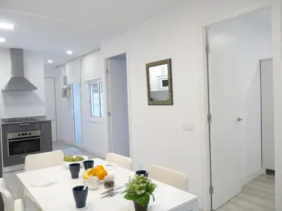 a white kitchen with a white table and chairs at MarBarcelona Apartments Mas in Hospitalet de Llobregat