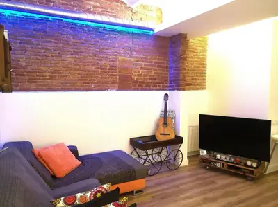 a living room with a couch and a television and a guitar at Roós, design loft near the sea. in Barcelona
