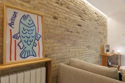a living room with a picture of a fish on a brick wall at Stylish Apartment near Plaça España in Barcelona