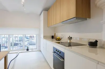 a kitchen with white countertops and wooden cabinets at Stylish Apartment near Plaça España in Barcelona