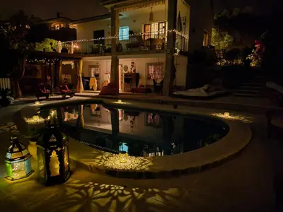 a swimming pool with lights in a backyard at night at Au Jardin d'Armand in Sant Pere de Ribes