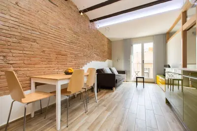 a brick wall in a living room with a table and chairs at Stay Barcelona Charming Gracia in Barcelona