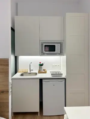 a white kitchen with a microwave and a sink at SD Habitación céntrica con baño y Kitchenette in Terrassa