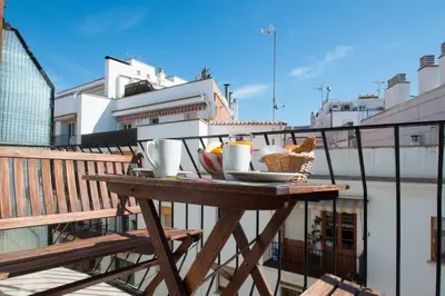 a table on a balcony with a plate of food on it at Hola! - Sitges Centric Apartment in Sitges