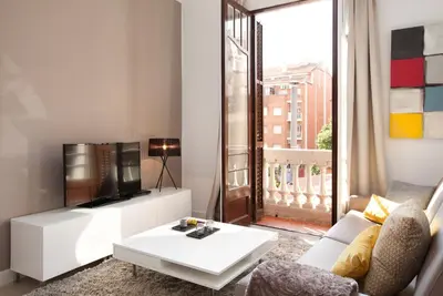 a living room with a white couch and a tv at Click&Flat Seneca Suites in Barcelona