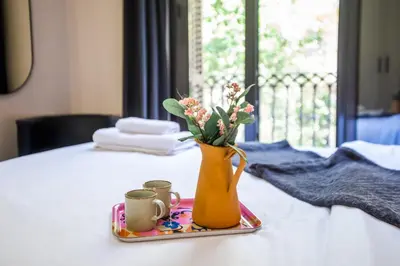 a vase with flowers on a tray with two cups at Tendency Apartments 9 in Barcelona