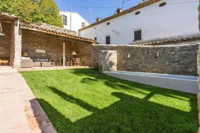 a yard with green grass next to a stone wall at Finca Can Romeu: alojamiento rural entre viñedos in Font-Rubí