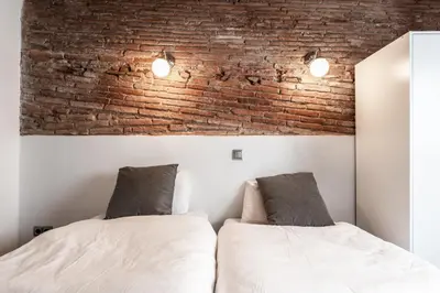 two beds in a bedroom with a brick wall at Apartamento La Boqueria 4 in Barcelona