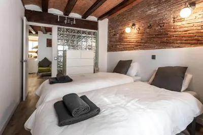 two beds in a room with a brick wall at Apartamento La Boqueria 4 in Barcelona