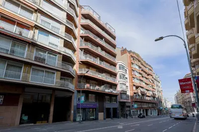 a bus is driving down a city street with tall buildings at Alcam Gold in Barcelona