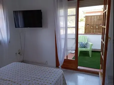 a bedroom with a bed and a window with a chair at Casa en Castelldefels a 5 min de la playa in Castelldefels