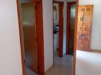 a room with three doors and a hallway with a kitchen at Casa en Castelldefels a 5 min de la playa in Castelldefels