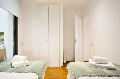 two beds in a room with white walls and wood floors at Les Corts Exclusive Apartments by Olala Homes in Barcelona