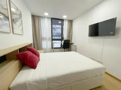 a bedroom with a white bed with a red pillow at MarBarcelona Suites Berlin in Barcelona