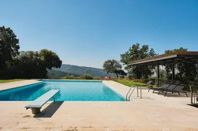 a swimming pool with two chairs and a pavilion at Villa in Barcelona region stunning biosphere in El Brull