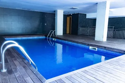 a swimming pool with blue water in a building at MERCE APARTMENT FORUM BARCELONA in Sant Adria de Besos