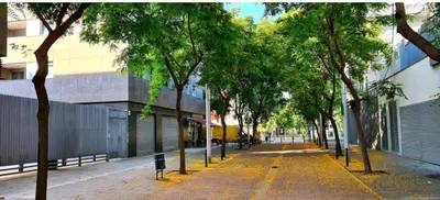 an empty street with trees in front of a building at MERCE APARTMENT FORUM BARCELONA in Sant Adria de Besos