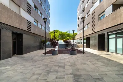 an empty courtyard between two tall buildings with potted trees at MERCE APARTMENT FORUM BARCELONA in Sant Adria de Besos