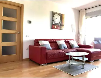 a red couch in a living room with a table at MERCE APARTMENT FORUM BARCELONA in Sant Adria de Besos