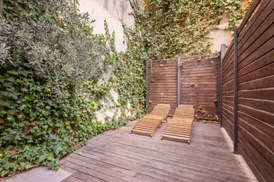 two chairs sitting on a wooden walkway next to a wall at Sweett - Casa Girona in Barcelona