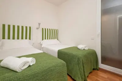 two beds in a room with green sheets and towels at Autèntic Barcelona Monumental in Barcelona
