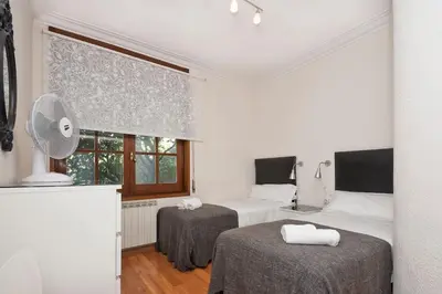 a bedroom with two beds and a fan and a window at Autèntic Barcelona Monumental in Barcelona