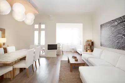 a white living room with a white couch and a table at Casanova Charm 4BDR Apartment in Barcelona
