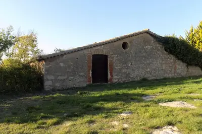 an old brick building with a door in a field at Can Vidal in Subirats