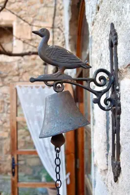 a bird on a bell attached to a building at Can Vidal in Subirats