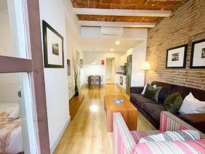 a living room with a couch and a brick wall at Boutique Pare Lainez- 2 BR Sagrada Famlia with balcony in Barcelona