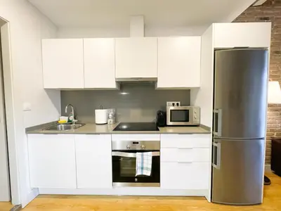 a kitchen with white cabinets and a stainless steel refrigerator at Boutique Pare Lainez- 2 BR Sagrada Famlia with balcony in Barcelona