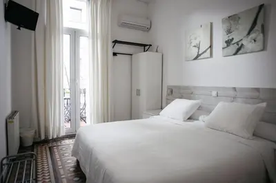 a white bedroom with a large bed and a window at Hostal Eixample in Barcelona