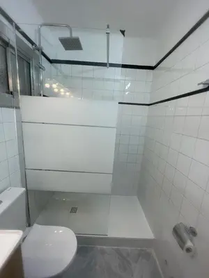 a white bathroom with a toilet and a shower at Alojamiento Calma in Hospitalet de Llobregat