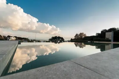a reflection of clouds in a pool of water at Hotel Sorli Emocions in Vilassar de Dalt
