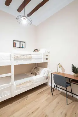 a bedroom with white bunk beds and a desk at Casa familiar junto al mar en Arenys de Mar in Arenys de Mar